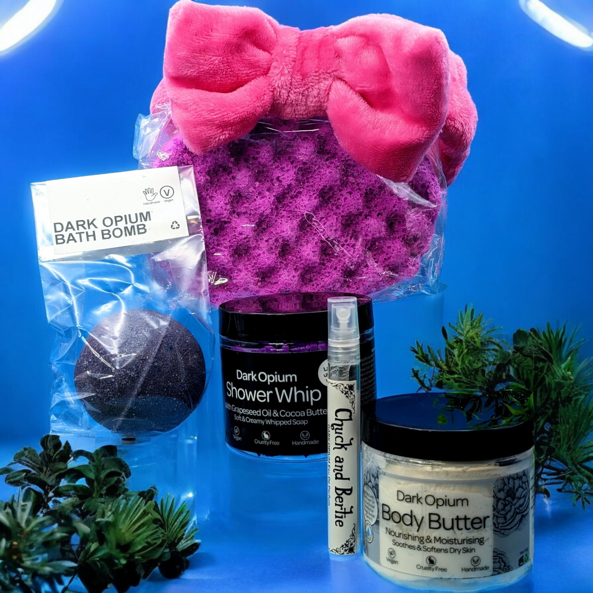 The products from the Dark Opium Bath and Body Set are positioned between greenery, on a blue background