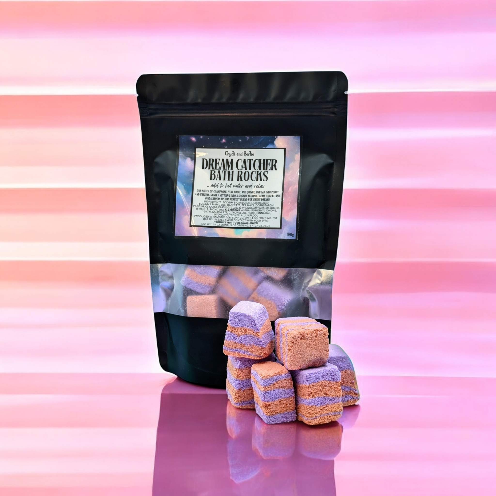 PINK AND WHITE SUBTLY STRIPED BACKGROUND, WITH A LARGE BLACK BAGS OF LILAC AND ORANGE STRIPED PIECES OF BATH ROCKS