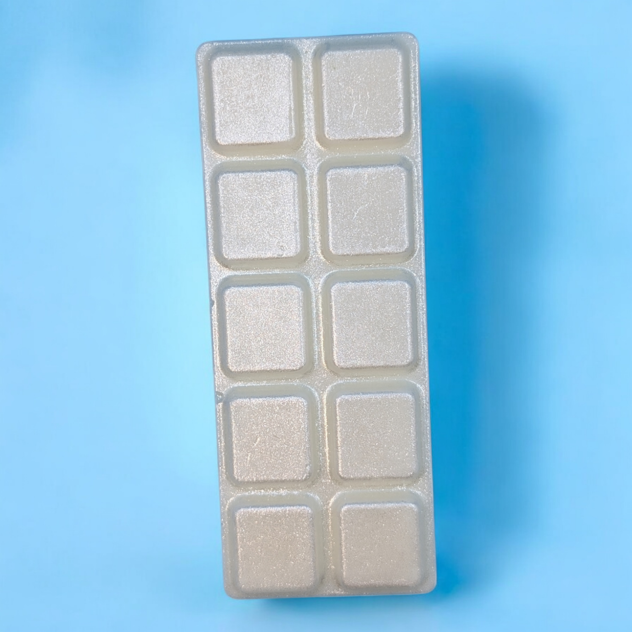 A silvery lilac coloured wax bar on a blue background